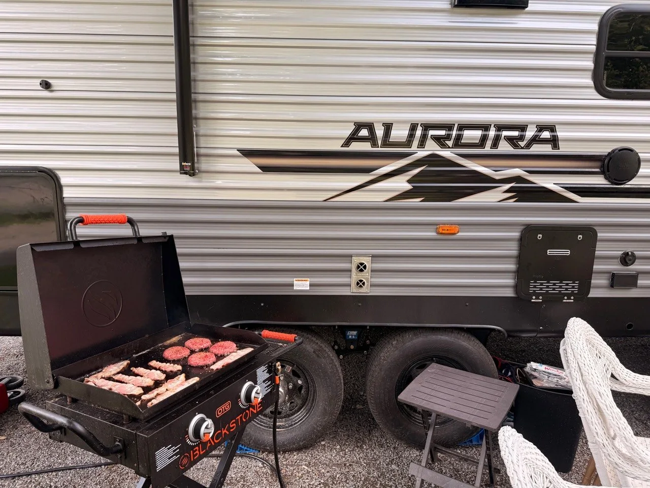 Blackstone griddle connected by a propane hose beside our Aurora camper