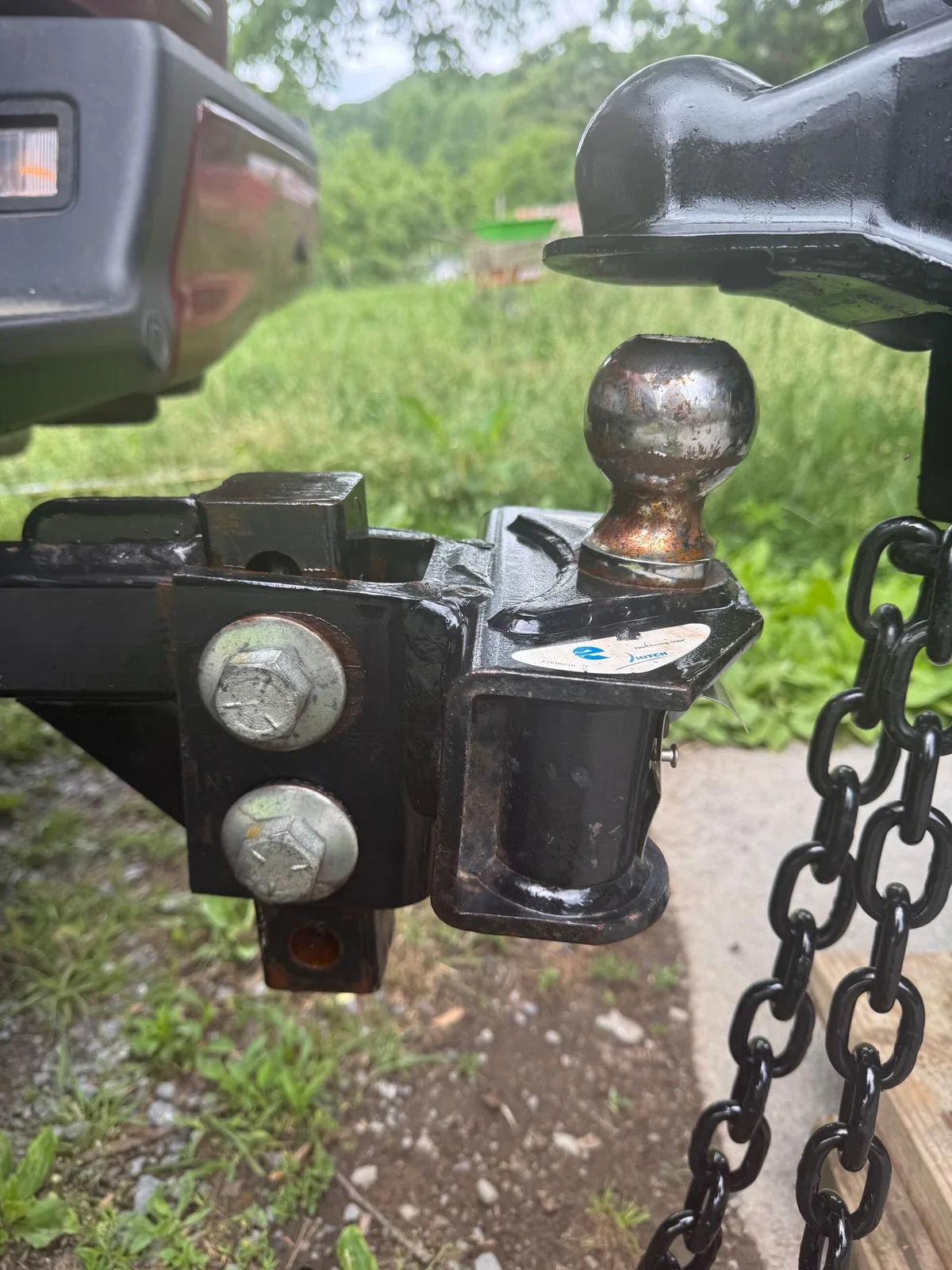 Close view of a trailer coupler raised above the hitch ball, not yet coupled