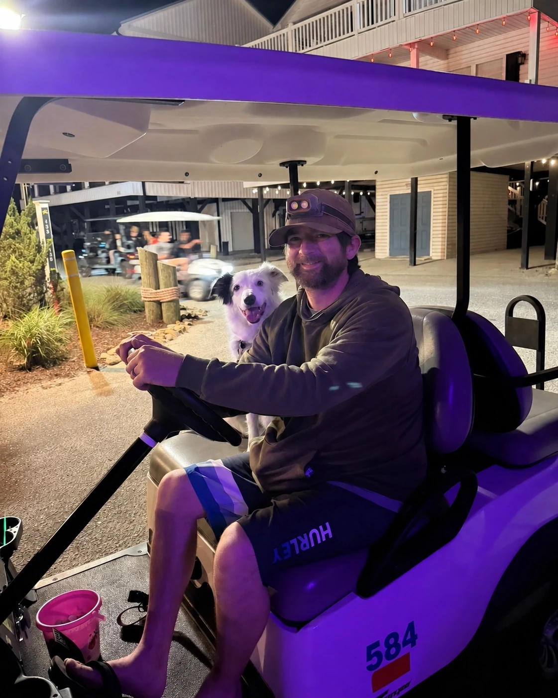 Jason and border collie Dolly riding an Ocean Lakes golf cart at night